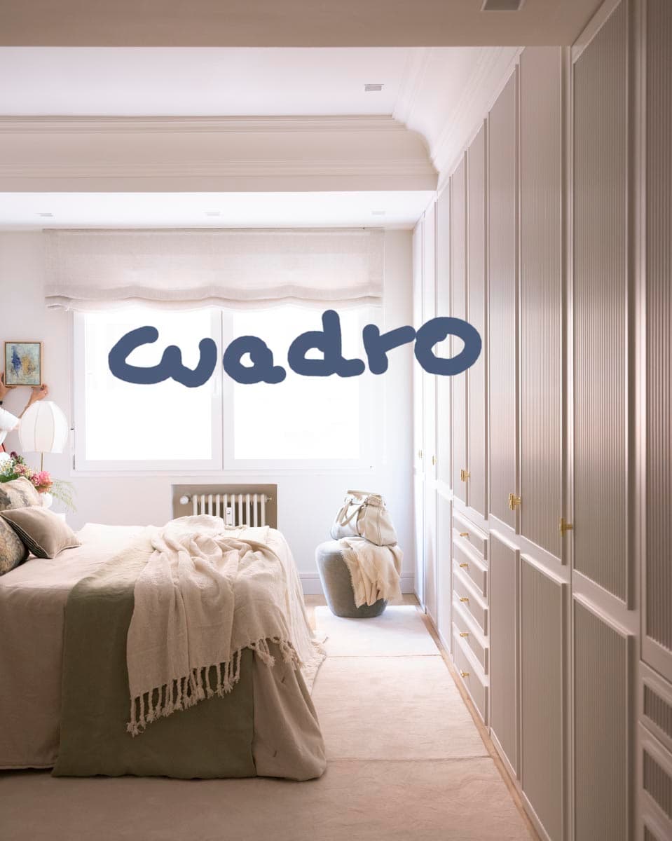 Dormitorio con armario de frente estriado en gris perla con tiradores de latón, cama con ropa de cama en tonos tierra y verde oscuro, y puf redondo de terciopelo gris al pie. La imagen muestra el sello editorial de la revista Cuadro superpuesto, indicando su publicación en prensa especializada.
